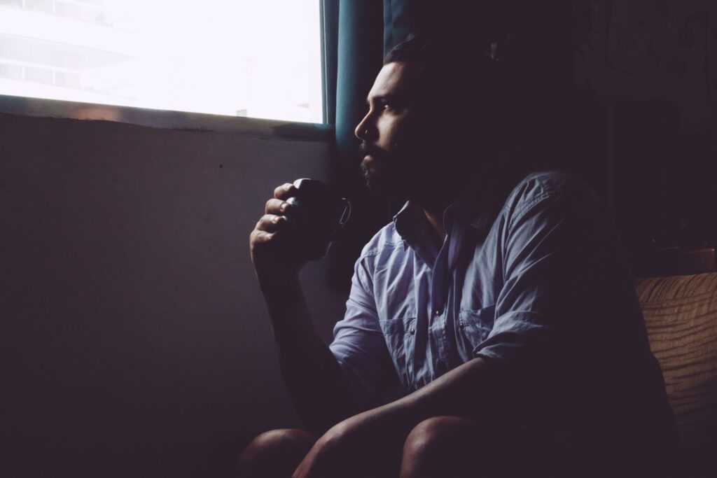 man drinking a mug of coffee while looking out the window