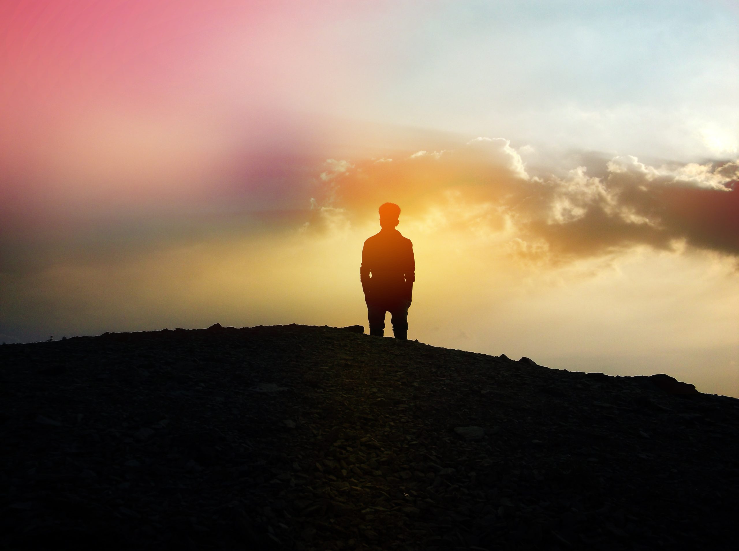 man standing on a mountain looking out at the clouds