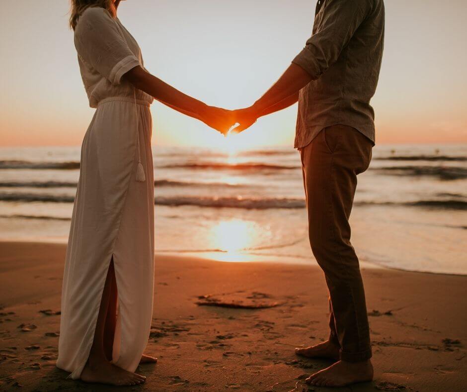 Couple holding hands on a beach at sunset 