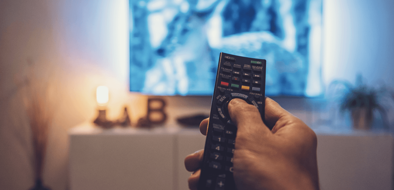Unidentified man hand holding remote in front of television about to watch movie