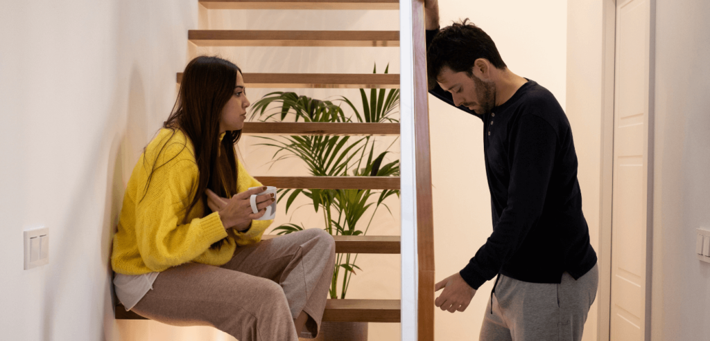 Young couple looking looking serious having a conversation inside the house in the staircase