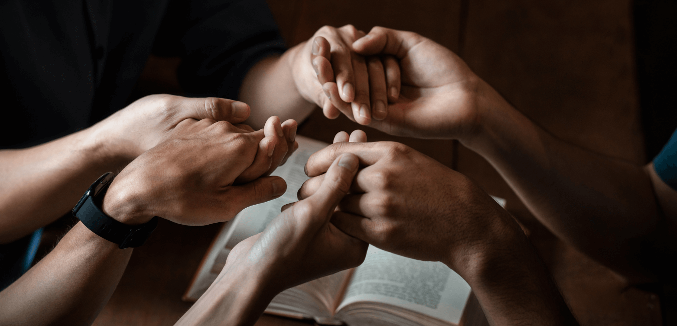 Close up shot of group holding hands praying and showing unity