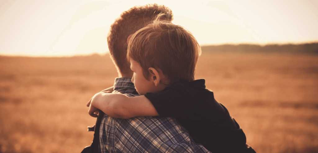 Man carrying his child in outdoors at sunset