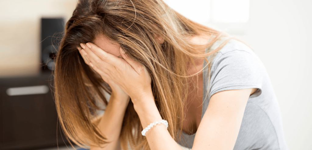 Woman sitting in a room looking depressed with her hand on her face