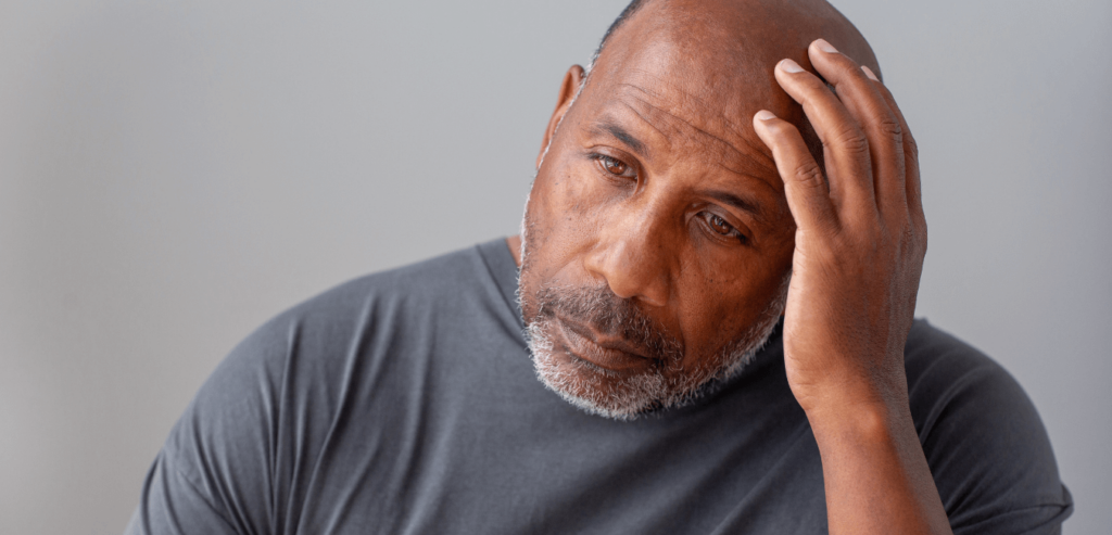 Man looking problematic sitting on corner with one hand on his head