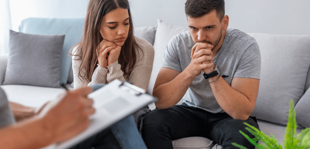 Therapist taking notes talking to a couple sitting on couch in a room