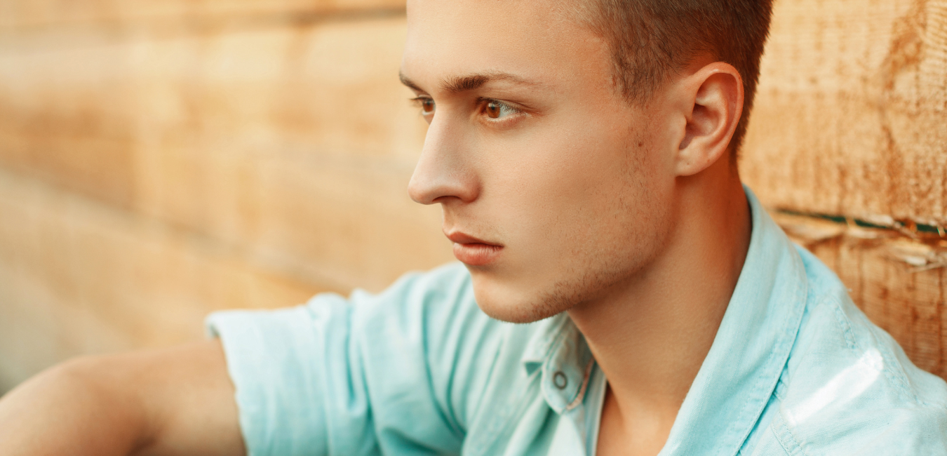 Young man sitting alone in corner looking far looking unhappy