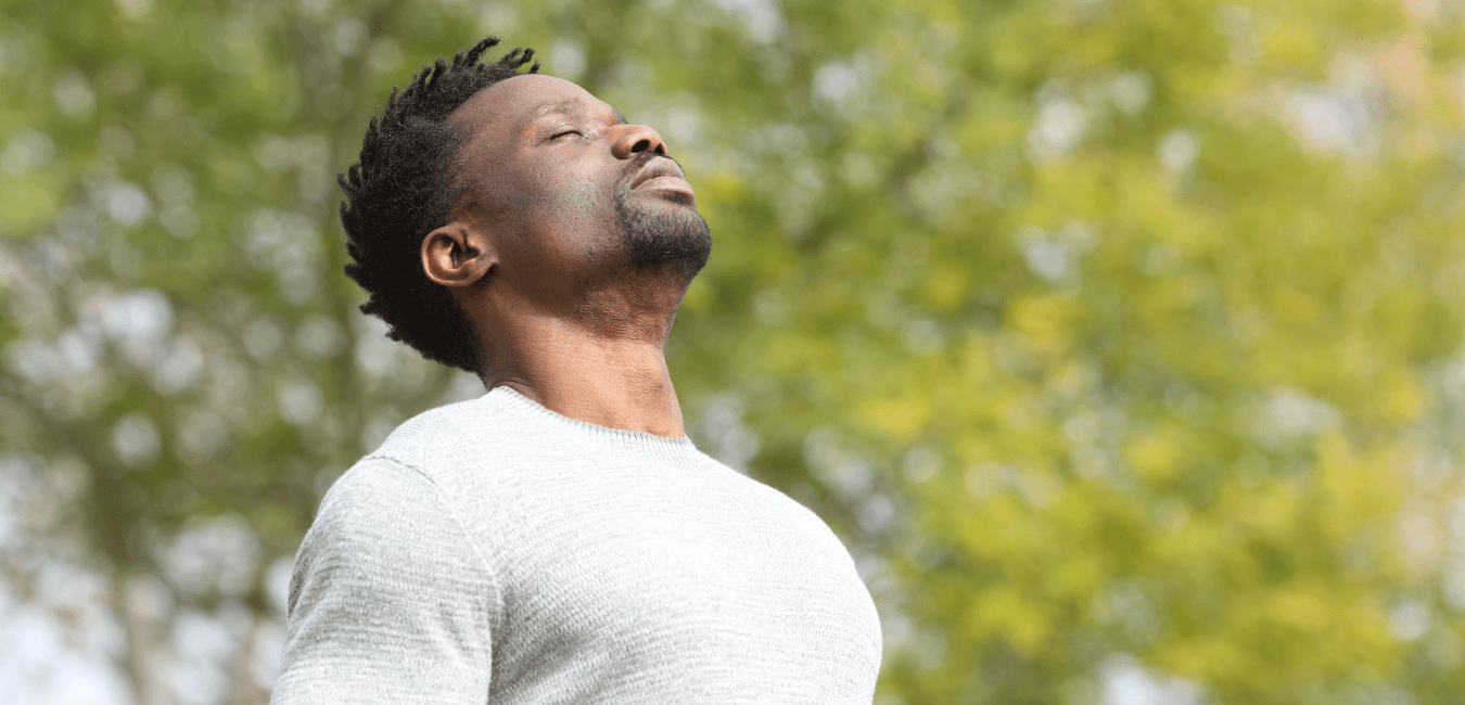 African man standing breathing deeply outside under the sun