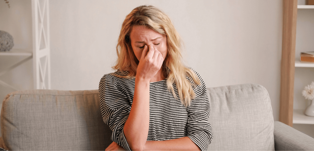 Blonde woman sitting on a couch, emotional and crying at home