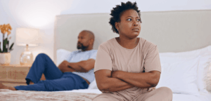 Couple sitting on bed looking away not talking after fight