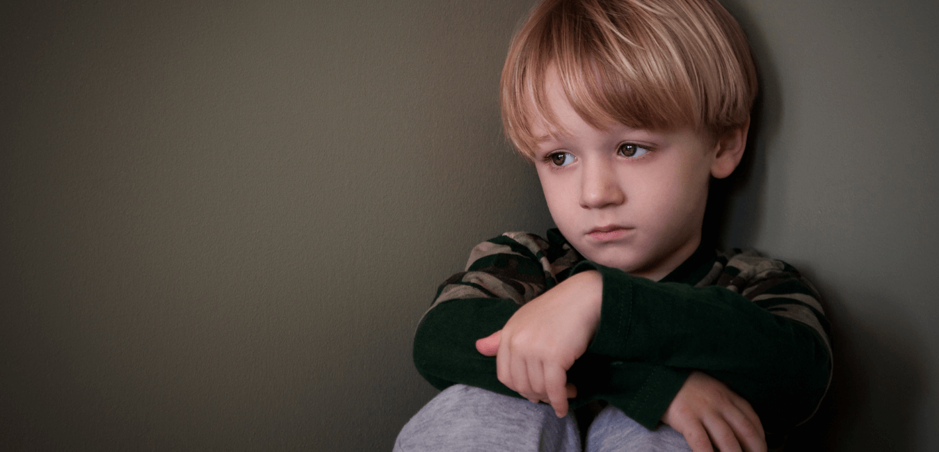 Child sitting quietly, and alone in the corner in house looking sad