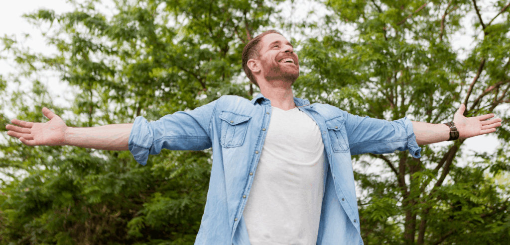 Man in open air outdoors looking happy with arms wide open