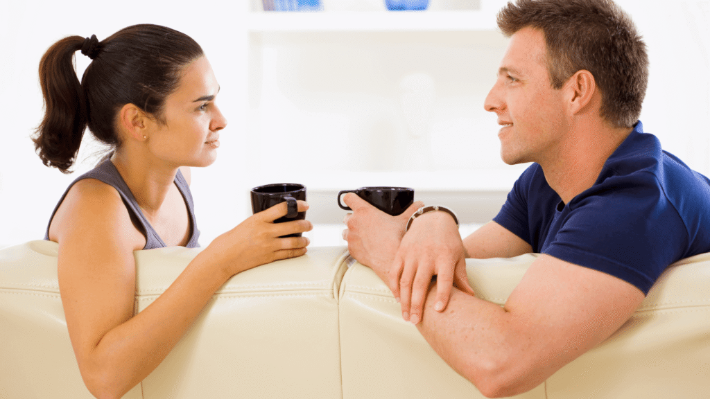 Couple sitting on a couch, talking while holding a mug