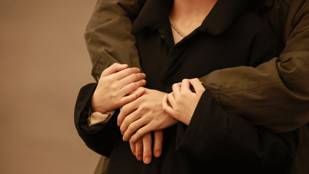 Close-up shot of a man hugging his partner outdoors at sunset.