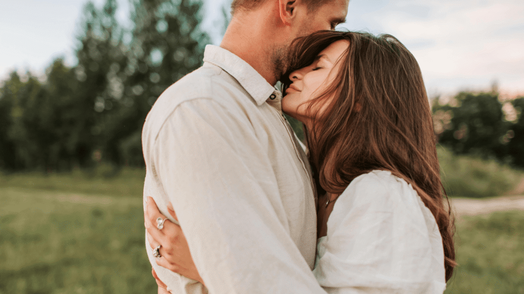 Young couple embracing outdoors, appearing relaxed and in love.