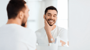 Man standing in front of bathroom mirror, smiling warmly at himself