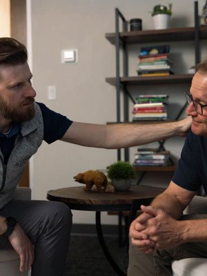 A therapist offering support by placing a reassuring hand on a client’s shoulder during a one-on-one session, reflecting empathy, trust, and compassionate guidance.